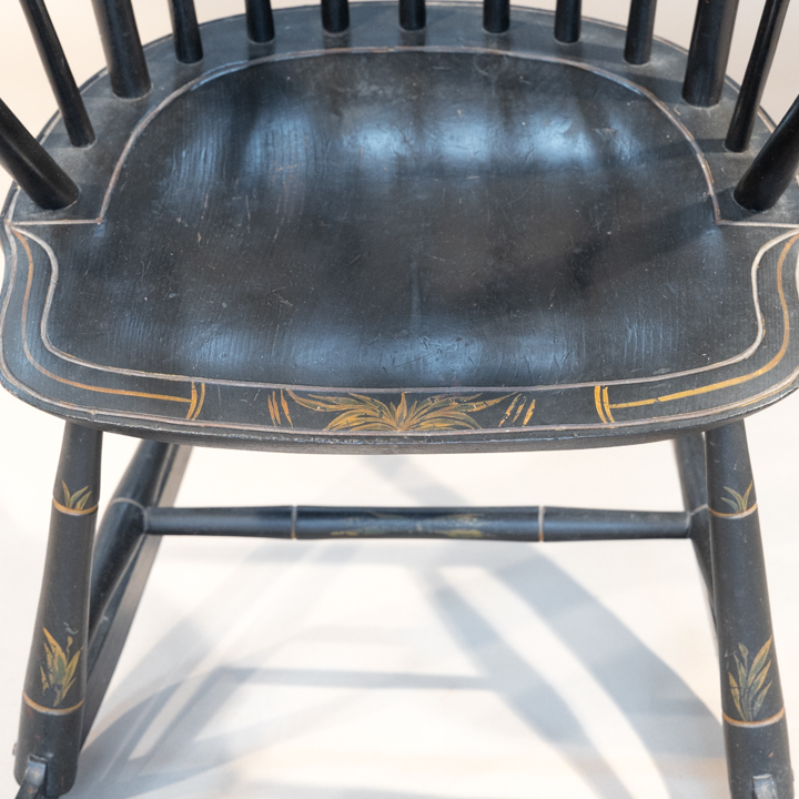 A rod backed windsor rocker with elongated step-down crest rail